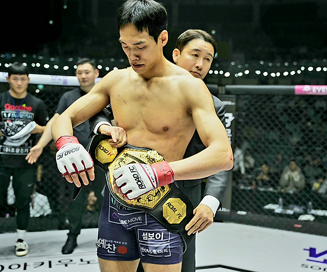 윤태영이 2025년 12월 서울특별시 중구 장충체육관 초대 로드FC 웰터급 타이틀 획득 후 대한MMA총협회 정문홍 회장에 의해 챔피언 벨트를 허리에 두르고 있다. 사진=세계격투스포츠협회