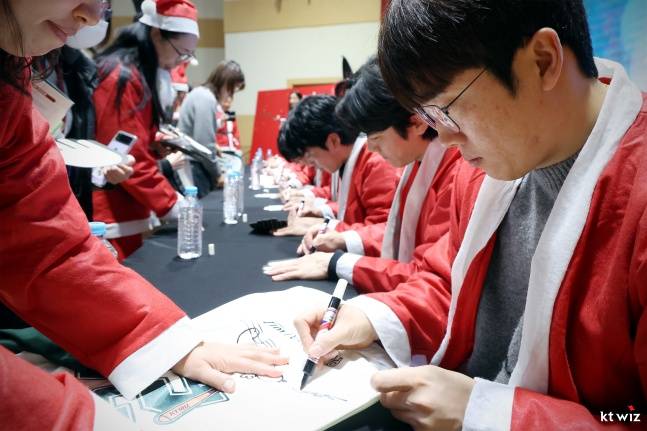 허경민(맨 오른쪽)과 KT 선수단이 19일 수원시청 대강당에서 열린 2025 수원 사랑의 산타 행사에 참가한 자원봉사자들에게 사인하고 있다. /사진=KT 위즈 제공