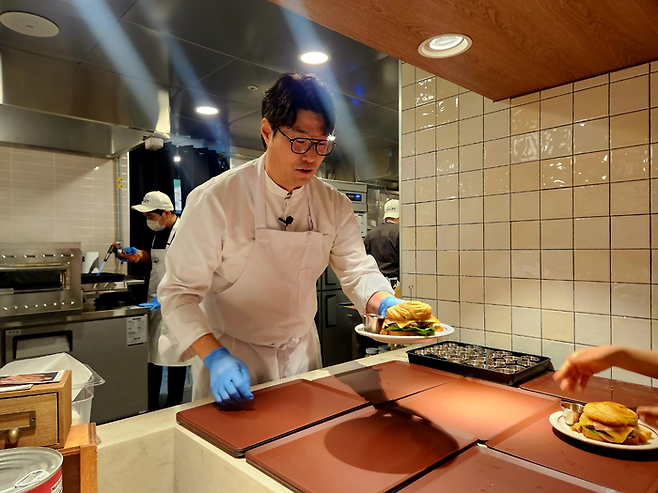 19일 ‘하우스 오브 애슐리’에서 애슐리퀸즈와 협업한 오세득 셰프가 직접 만든 ‘한우 비프웰링턴 버거’를 나눠주고 있다.  <박윤예 기자>