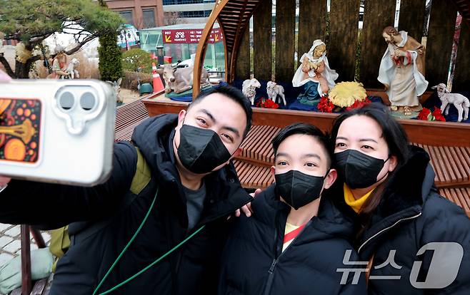크리스마스 이브를 하루 앞둔 23일 서울 중구 명동대성당 앞에 설치된 성탄 구유에서 외국인 관광객들이 기념사진을 찍고 있다. 2025.12.23/뉴스1 ⓒ News1 이호윤 기자