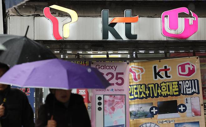 휴대전화를 개통할 때 신분증만 제시하던 것에서 패스 앱을 이용해 얼굴 사진을 찍어 본인임을 확인받는 절차가 시범 실시되는 23일 서울의 한 휴대폰 매장 앞을 시민들이 오가고 있다. 연합뉴스