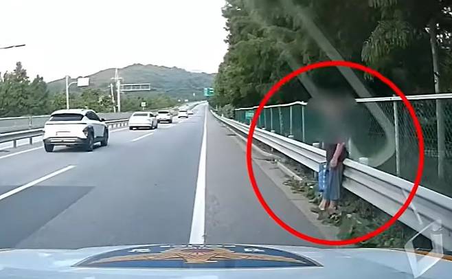 A screenshot from police video footage shows an elderly man walking along the shoulder of a highway in Asan, South Chungcheong Province. (National Police Agency)