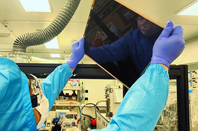 한국화학연구원에서 기술을 이전받고 상용화를 위해 협업 중인 대면적 페로브스카이트 태양전지 기판을 보고 있는 엘케이켐 연구원. 한국화학연구원