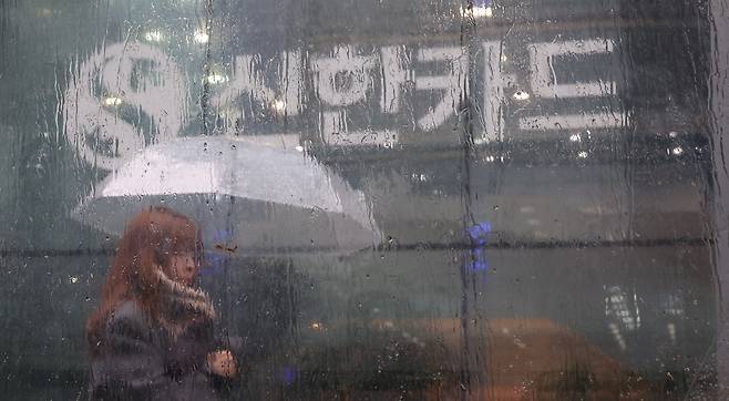 23일 오후 겨울비가 내리는 가운데 서울 중구 을지로 신한카드 본사 앞을 한 행인이 지나고 있다. 이날 신한카드는 신한카드 가맹점 대표자의 휴대전화번호를 포함해 개인정보 약 19만건이 유출된 것으로 추정돼 개인정보보호위원회에 신고했다고 밝혔다.  이승환 기자