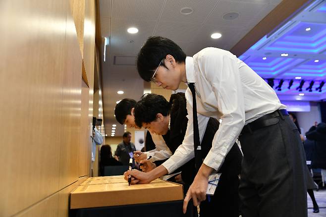 '세계기선전' 출전 국수들이 바둑판에 사인을 하고있다. 사진 맨 앞은 신진서 9단. 한국기원 제공