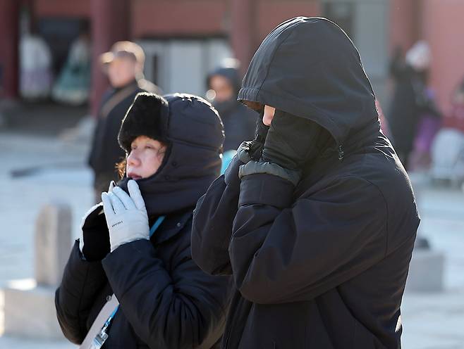 People clad in thick coats, mufflers and gloves walk on a street near Gyeongbok Palace in Jongno District, central Seoul, on Dec. 25. [NEWS1]