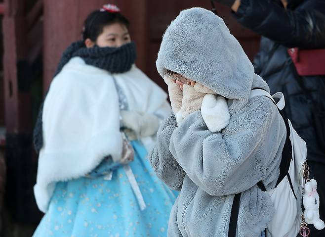 People clad in thick coats, mufflers and gloves are seen at Gyeongbok Palace in Jongno District, central Seoul, on Dec. 25. [NEWS1]