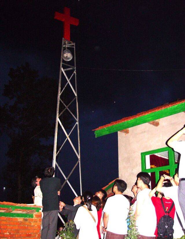 광림교회 청년들이 2001년 북한 땅이 보이는 중국의 한 옥수수밭에 세운 교회에서 종을 치고 있는 모습.