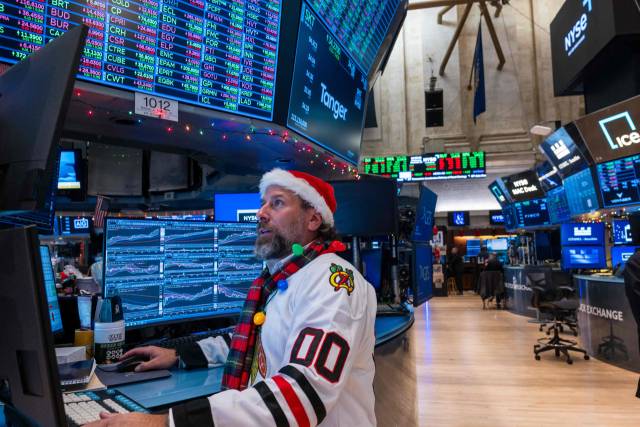 24일(현지 시간) 미국 뉴욕증권거래소(NYSE)의 한 거래중개인이 산타 클로스 복장을 한 채 증시 현황판을 살피고 있다. AFP연합뉴스