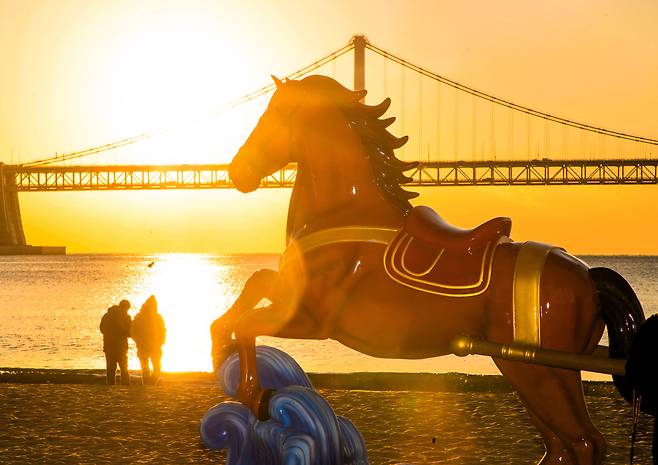 22일 오전 부산 수영구 광안리해수욕장에 설치된 붉은 말 조형물 뒤로 해가 떠오르고 있다. /김동환 기자