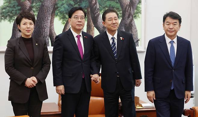 Kim Byung-kee, the floor leader of the Democratic Party, center right, and Song Eon-seog, the floor leader of the People Power Party, center left, pose for reporters while shaking hands during a meeting of floor leaders on pending issues, including a special counsel probe into the Unification Church, at the National Assembly in Yeouido, western Seoul, on Dec. 22. Kim Eun-hye, the senior policy deputy floor leader of the People Power Party, stands to Song's left, and Moon Jin-seog, the senior floor operations deputy leader of the Democratic Party, to Kim's right. [YONHAP]