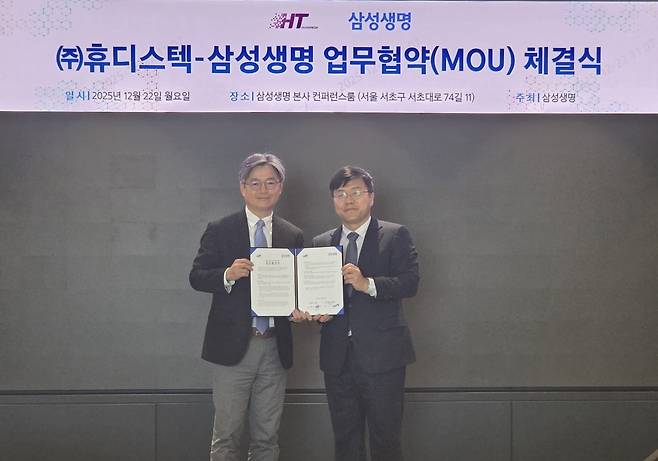 황찬식 휴디스텍 대표(왼쪽)와 오성용 삼성생명 전략영업본부 본부장이 업무협약서를 들어보이고 있다. 휴디스텍 제공.