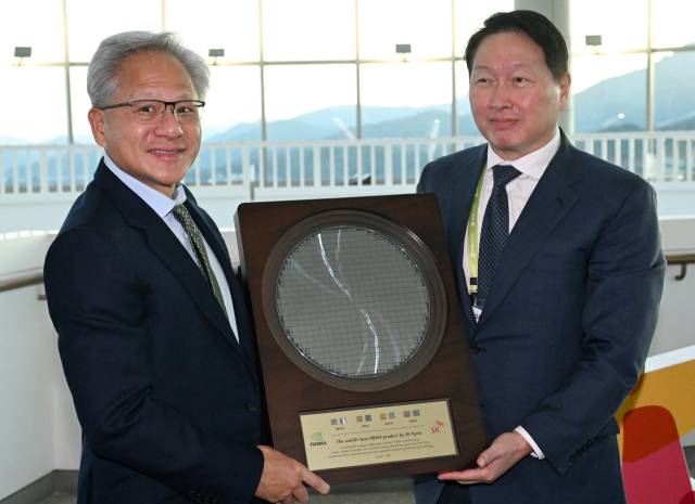 젠슨 황(왼쪽) 엔비디아 CEO가 10월 31일 경북 경주시 경주예술의전당에서 열린 아시아태평양경제협력체(APEC) CEO 서밋에 참석해 최태원 SK그룹 회장 겸 대한상의 회장으로부터 SK하이닉스의 HBM4 반도체 웨이퍼를 선물로 받고 있다. 뉴스1