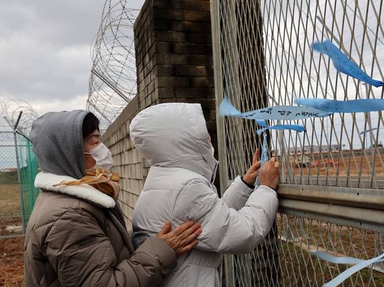 12·29 제주항공 여객기 참사 1주기를 앞둔 24일 전남 무안국제공항에서 유가족들이 활주로를 바라보며 추모 리본을 달고 있다. 뉴스1