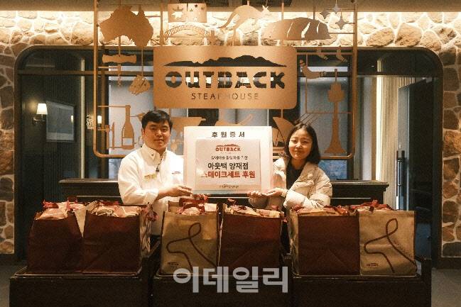 아웃백 양재점 조주호 매니저와 한우리정보문화센터 정예진 복지사가 러브백 캠페인 기념촬영을 하고 있다.(사진=아웃백)
