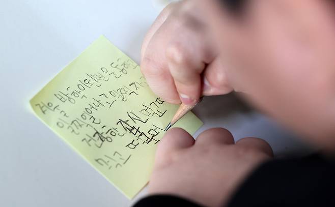 A child writes a memo at an elementary school in Dongdaemun District, central Seoul, on Dec. 24. The message reads, "I want to work out, get up early, sleep early and eat healthy during the winter vacation." [NEWS1]