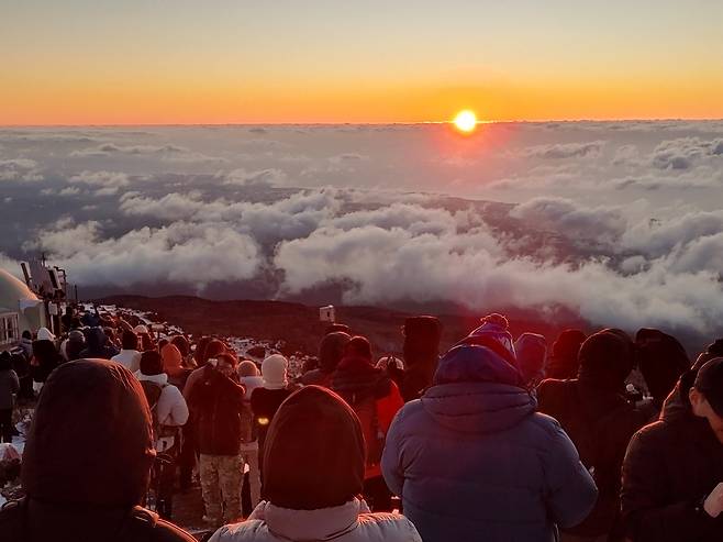 Hikers watch the first sunrise of 2025 from the slopes of Mount Halla on Jeju Island on Jan. 1. [YONHAP]