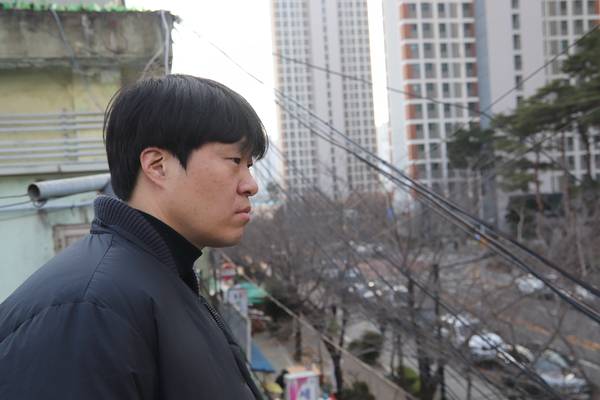 자신이 태어나 살고 있는 마산을 소재로 작업하는 설치미술가 최수환이 회원1동 오래된 건물에서 맞은면 회원2동 재개발로 들어선 아파트 단지를 바라보고 있다. /이서후 기자