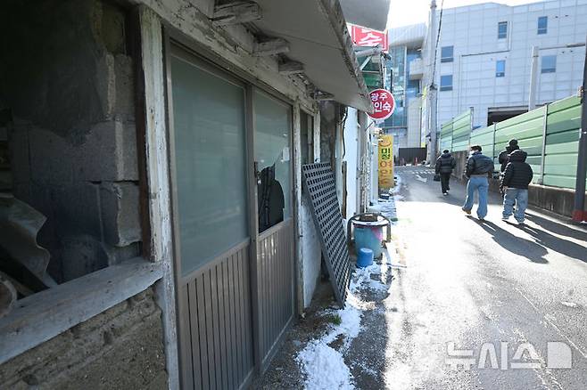 [광주=뉴시스] 이현행 기자 = 지난 26일 오후 광주 광산구 광주송정역 인근에서 시민들이 깨지고 부서진 폐건물과 여인숙을 쳐다보며 걷고 있다. 2025.12.30. lhh@newsis.com