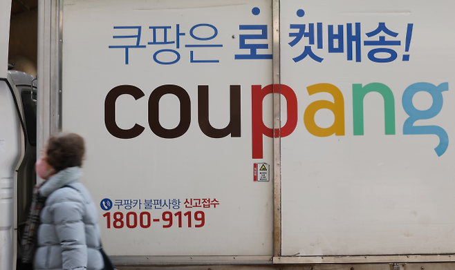 서울에 있는 한 쿠팡 물류센터에 쿠팡의 로고가 적힌 배송 트럭 앞으로 시민이 지나가고 있다. 쿠팡은 최근 대규모 고객 개인정보 유출 사태를 비롯해 잇따른 배달 노동자 사망 사고로 곤욕을 치르고 있다. 서울신문DB