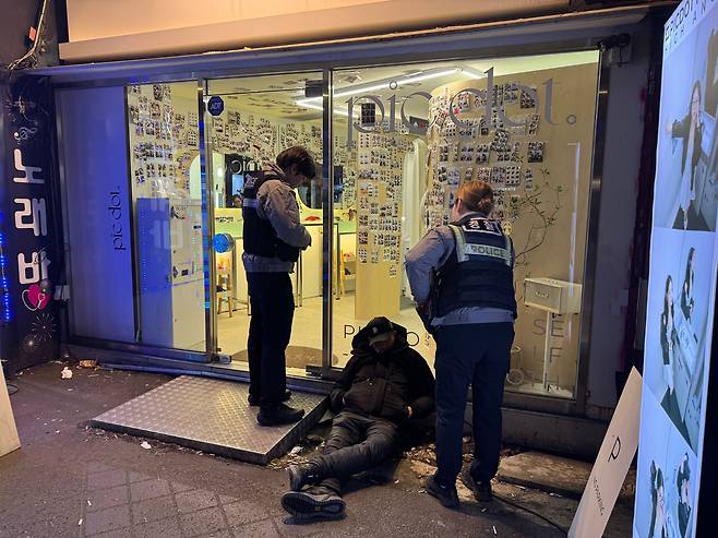 지난달 30일 밤 서울 영등포구의 한 무인 사진관 앞에 중년 남성이 술에 취해 쓰러져 있다. 경찰이 출동해 남성을 살피고 있다./윤성은 기자