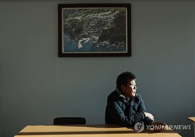 '옛 마을이 그립다' (영덕=연합뉴스) 윤관식 기자 = 2일 경북 영덕군 영덕읍 석리의 마을회관에서 이미상 석리 이장이 마을의 옛 모습이 담긴 사진 아래에서 생각에 잠겨 있다. 석리는 지난해 3월 산불 피해로 마을 전체가 불에 타는 피해를 봤다. 2026.1.2 psik@yna.co.kr