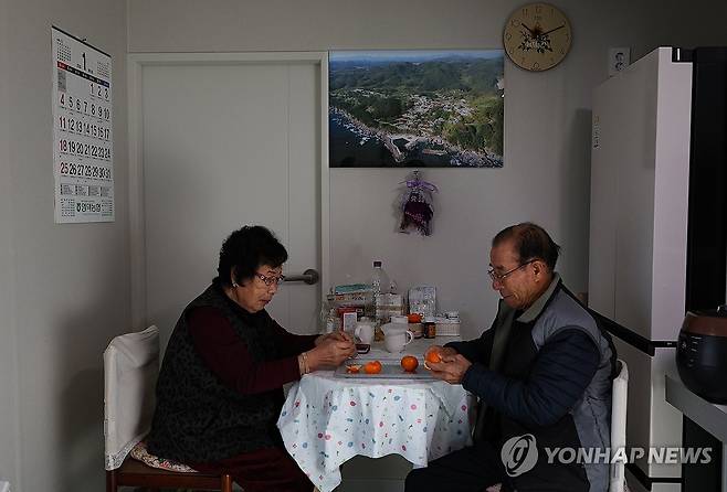 산불 임시주택에 걸린 옛 마을 모습 (영덕=연합뉴스) 윤관식 기자 = 2일 경북 영덕군 영덕읍 석리 임시주택에서 김재봉·윤금자 부부가 식탁에 앉은 가운데 마을의 옛 모습이 담긴 사진이 걸려 있다. 석리는 지난해 3월 산불 피해로 마을 전체가 불에 타는 피해를 봤다. 2026.1.2 psik@yna.co.kr