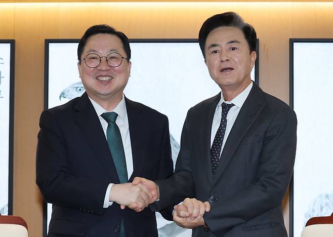 South Chungcheong Gov. Kim Tae-heum, right, and Daejeon Mayor Lee Jang-woo shake hands ahead of a meeting on the proposed administrative merger of Daejeon and South Chungcheong at the South Chungcheong Provincial Government Office on the morning of Dec. 24, 2025. [NEWS1]