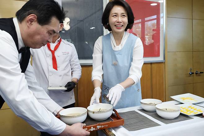 Korean first lady Kim Hea Kyung, right, serves Korean cuisine at a luncheon meeting for Chinese women — who serve as a bridge between Korea and China — at the Korean ambassador to China’s residence in Beijing on Jan. 5. [JOINT PRESS CORPS]