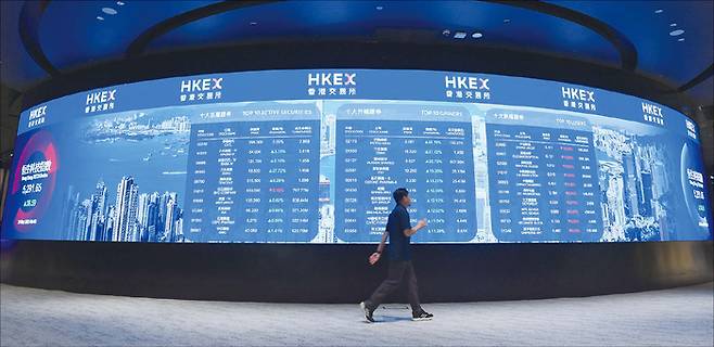 2026년 중화권 증시에 대한 긍정적 전망이 주를 이룬다. 사진은 2025년 5월 20일 홍콩증권거래소에서 한 남성이 전광판 앞을 지나가고 있다. (Xinhua=연합뉴스)