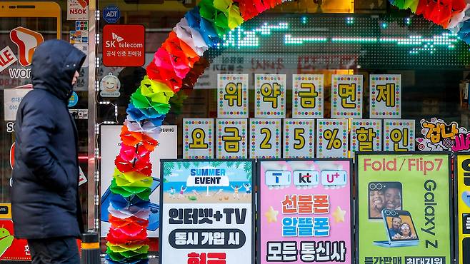 [서울=뉴시스] 정병혁 기자 = 4일 서울시내 휴대폰판매점 앞에서 시민들이 이동하고 있다. KT의 번호이동 이탈이 위약금 면제 시행 이후 빠르게 확대되며 사흘간 누적 5만명을 넘어섰다. 이탈 고객의 이동은 SK텔레콤에 가장 많이 집중된 것으로 나타났다. 이동통신업계에 따르면 KT가 위약금 면제를 시작한 지난해 12월 31일부터 이달 3일까지 KT와 기존 계약을 해지한 가입자는 누적 5만2661명으로 집계됐다. 2026.12.04. jhope@newsis.com