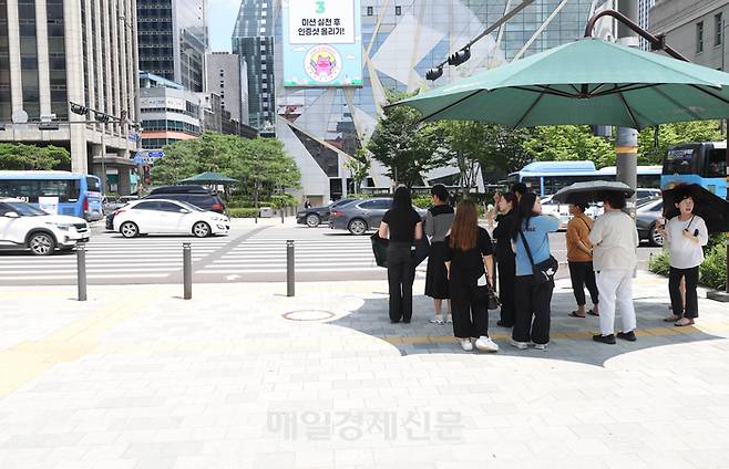 2025년 7월 22일 폭염에 지친 시민들이 횡단보도에 마련된 그늘에서 태양을 피하고 있다. [이충우 기자]