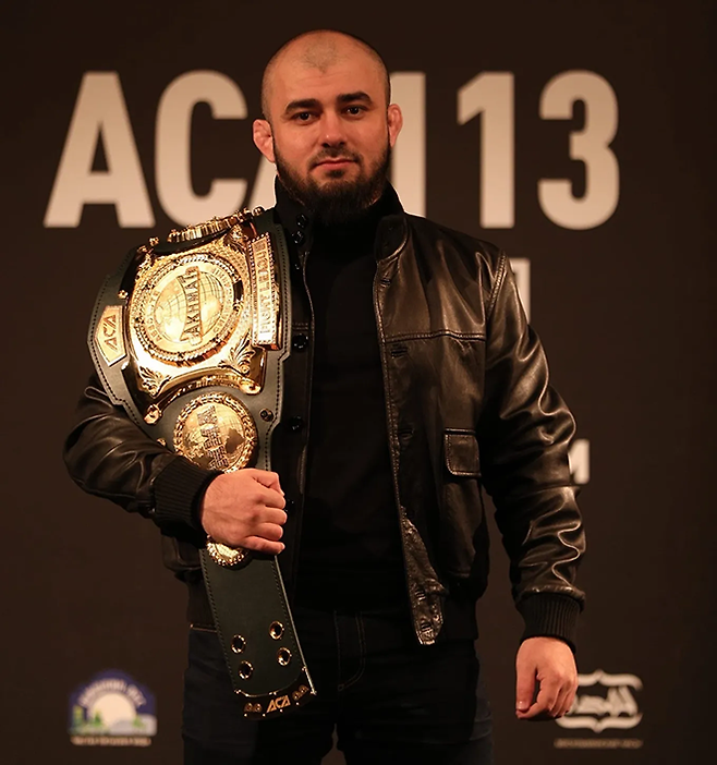 아슬란베크 바다예프 부회장이 2020년 11월 1만2273석 규모 러시아 모스크바 픗프 아레나에서 열린 ACA 113번째 최고 등급 대회 메인이벤트를 홍보하기 위해 플라이급 챔피언 벨트를 들고 있다. 사진=ООО АБСОЛЮТНЫЙ ЧЕМПИОНАТ АХМАТ