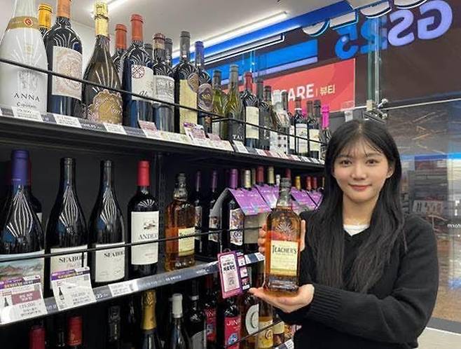 모델이 GS25에서 출시 후 품절대란을 일으킨 1만원대 가성비 위스키 '티처스' 상품을 들고 포즈를 취하고 있다. GS리테일 제공
