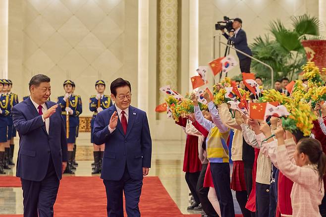President Lee Jae Myung, right, and Chinese President Xi Jinping wave to children during an official welcoming ceremony at the Great Hall of the People in Beijing before their bilateral summit on Jan. 5. [JOINT PRESS CORPS]