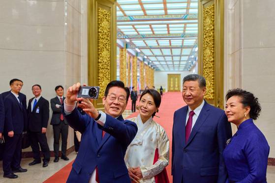 From left, President Lee Jae Myung takes a selfie with first lady Kim Hea Kyung, Chinese President Xi Jinping and first lady Peng Liyuan with a Xiaomi smartphone during a state dinner at the Great Hall of the People in Beijing on Jan. 5. [JOINT PRESS CORPS]