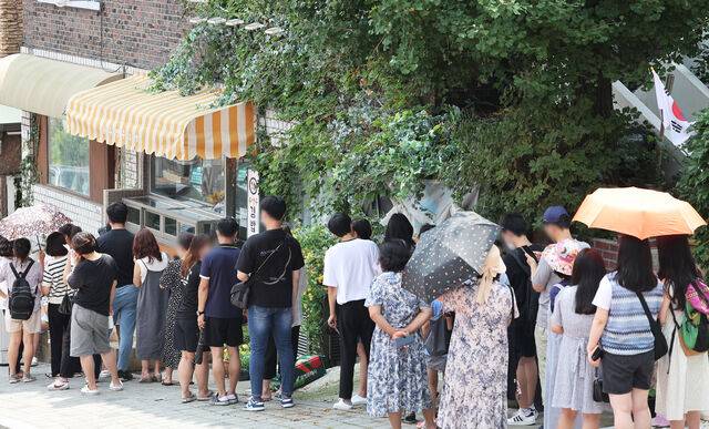 2022년 8월 드라마 ‘이상한 변호사 우영우’ 촬영지인 경기 수원시 팔달구 행궁동의 한 식당에 시민들이 입장을 기다리며 줄을 서 있다. 연합뉴스