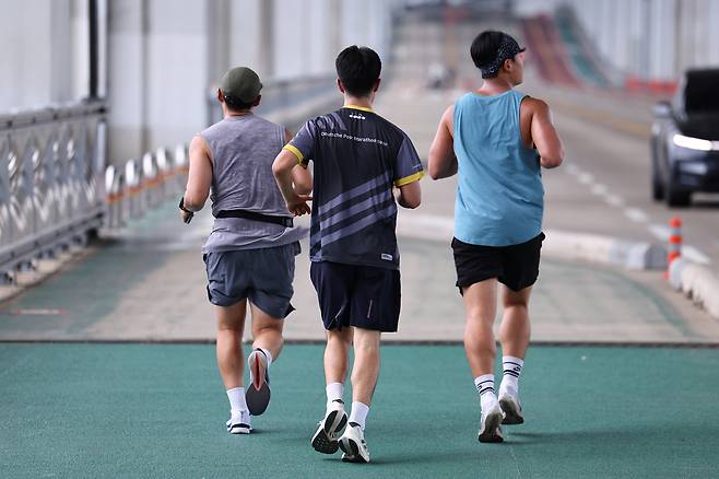Three men are running at a roadside in Seoul on Aug. 13, 2025. [YONHAP]