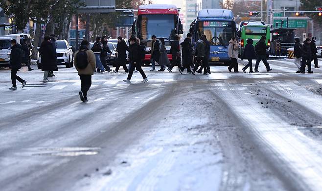 People walk among icy roads in Jongno District, central Seoul, on Dec. 5, 2025, following a heavy snowfall the previous night. [NEWS1]