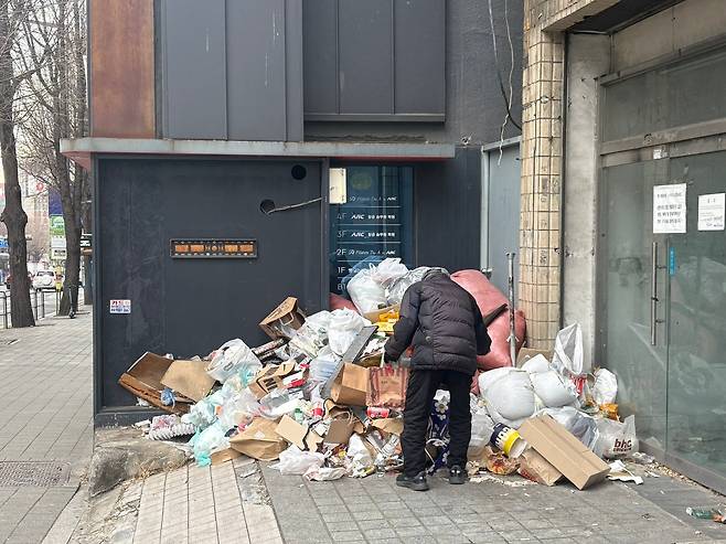 6일 오후 서울 서대문구 이대 거리 한 공실 상가 앞. 한 노인이 쓰레기 더미 속에서 폐지를 골라내고 있다./정동하 기자
