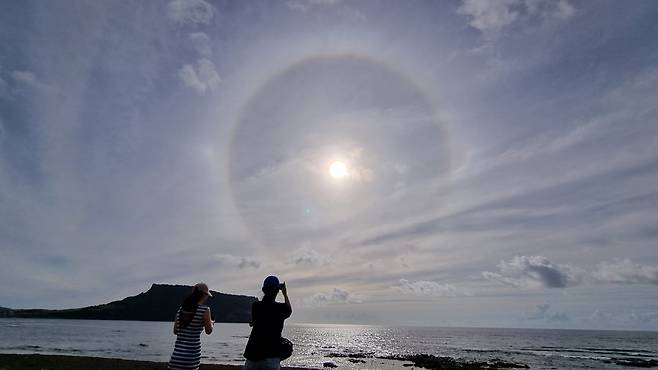 2022년 8월 9일 오전 제주 곳곳에서 햇무리가 보였다. 사람들이 성산 일출봉 위로 떠오른 햇무리를 촬영하고 있다./제주도의회