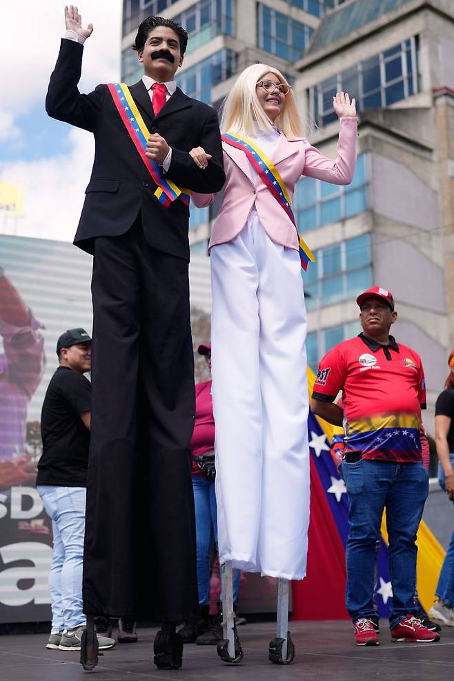[카라카스=AP/뉴시스] 9일(현지 시간) 베네수엘라 카라카스에서 니콜라스 마두로 전 대통령 부부를 흉내 낸 죽마 공연자들이 미국에 체포된 이들의 석방을 요구하는 집회에 참석해 정부 지지자들에게 손을 흔들고 있다. 2026.01.10.
