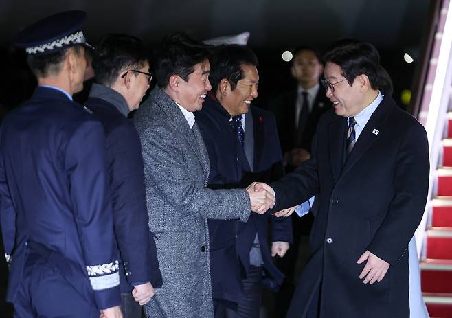 President Lee Jae Myung, right, greets presidential aides after returning from a four-day state visit to China at the Seoul Air Base in Seongnam, Gyeonggi, on Jan. 7. [JOINT PRESS CORPS]