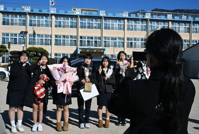 9일 창원시 진해구 진해여자중학교 마지막 졸업식에서 졸업생들이 교정을 배경으로 기념사진을 남기고 있다. /김승권 기자/