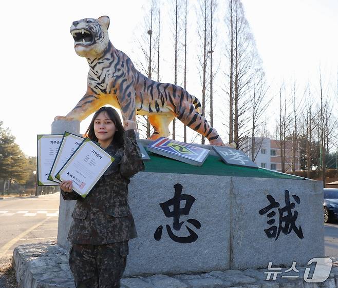 육군 2기갑여단 적오대대 이나라 중사가 부대를 상징하는 호랑이상 앞에서 기부증서를 들고 화이팅 포즈를 취하고 있다. (2기갑여단 제공, 재판매 및 DB금지)