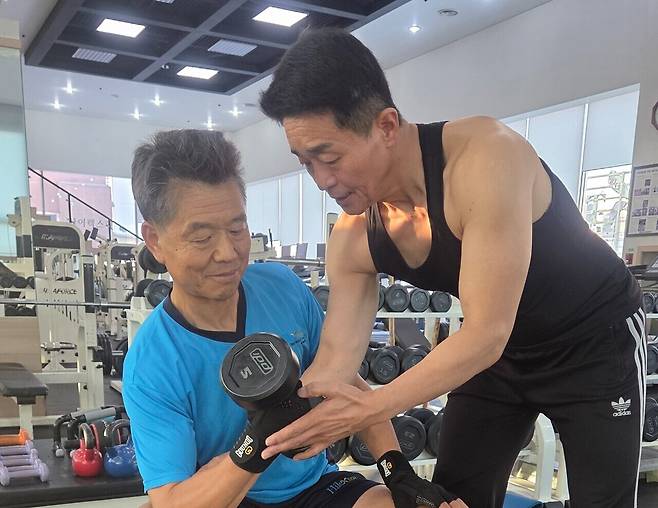 헬스 트레이너로 인생이모작을 시작한 김혁식씨(오른쪽)가 한 회원에게 운동방법에 대해 설명하고 있다. 김정규 기자