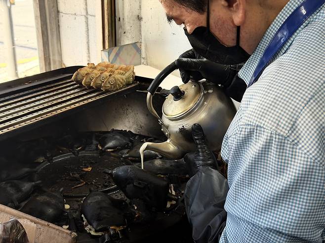Kim Jong-sik hand-pours batter into cast-iron molds at his bungeoppang stall near Namyeong Station, where lines often stretch an hour long for his famously overstuffed red bean pastries. (Moon Joon-hyun/The Korea Herald)