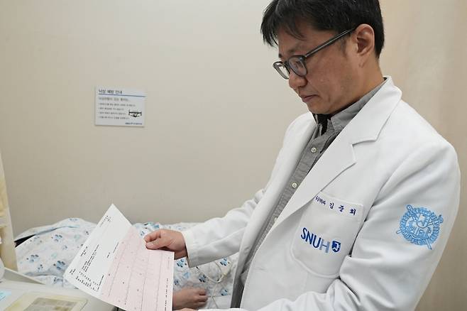 김중희 분당서울대병원 응급의학과 교수가 환자의 심전도 검사 결과지를 확인하고 있다. 김 교수는 “심전도 판독은 연차가 쌓인다고 해서 숙련도가 자동으로 유지되는 영역이 아니라서 작은 변화에도 판단이 엇갈리기 쉽다”면서 “바쁜 응급실의 부담을 덜어주기 위해 ‘ECG  버디’를 개발했다”고 말했다. [분당서울대병원]
