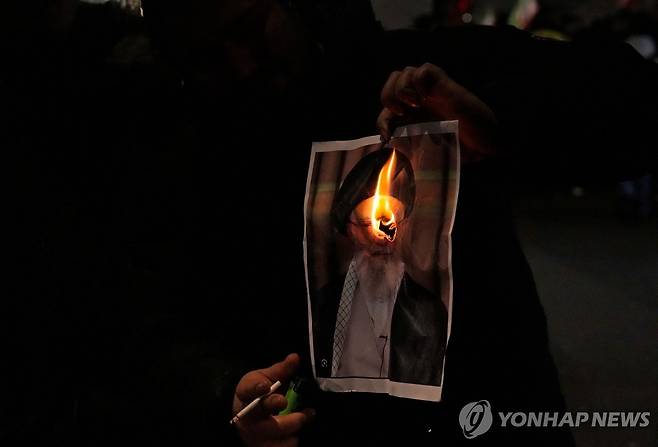 불타고 있는 하메네이 사진 [AFP=연합뉴스. 재판매 및 DB 금지] 11일 영국 런던에서 열린 이란 연대 집회에서 한 시위대가 이란 최고지도자 아야톨라 하메네이의 사진을 불태우고 있다.