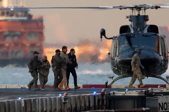 니콜라스 마두로 베네수엘라 대통령과 부인 실리아 플로레스가 지난 5일 헬기에서 내린 뒤 호송 요원들에게 이끌려 맨해튼의 남부연방지방법원으로 걸어가고 있다. 마약 관련 혐의 등으로 기소된 이들은 처음으로 미국 법정에 섰다. [로이터=연합뉴스]